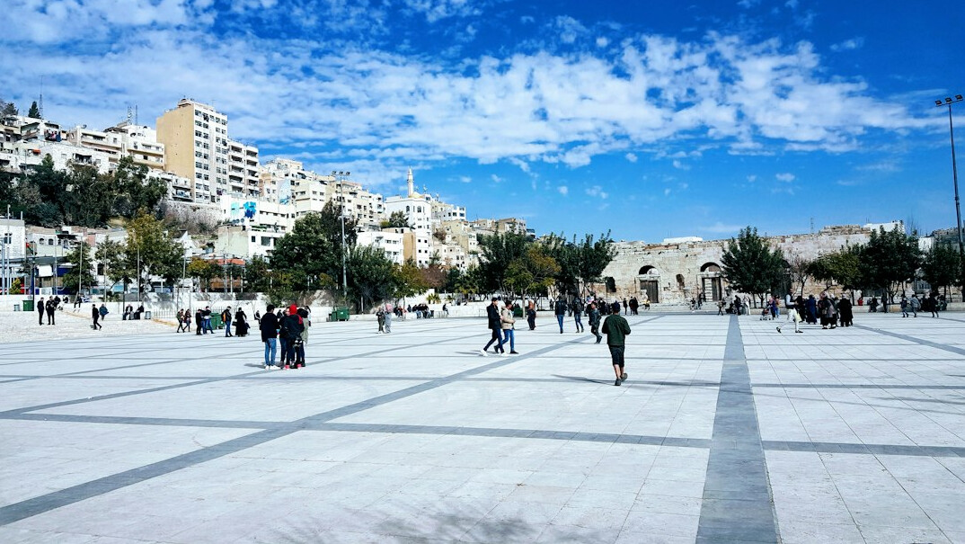 Anonymous crowd of people walking through a plaza seen from a distance